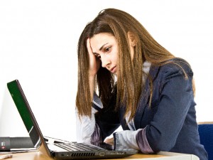 ノートパソコンの前で考える女性